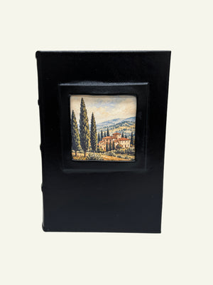 Black leather journal featuring a Tuscan village landscape in the front portrait window.