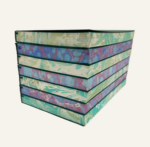 Stacked refillable journal inserts with marbleized edges in green and ivory and blue and burgundy
