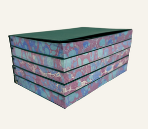Stack of marbleized edge refillable journal inserts in blue and burgundy