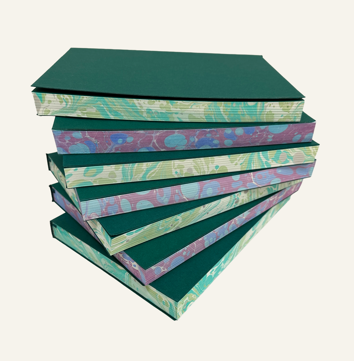Fanned out refillable journal inserts with marbleized edges in green and ivory and blue and burgundy 
