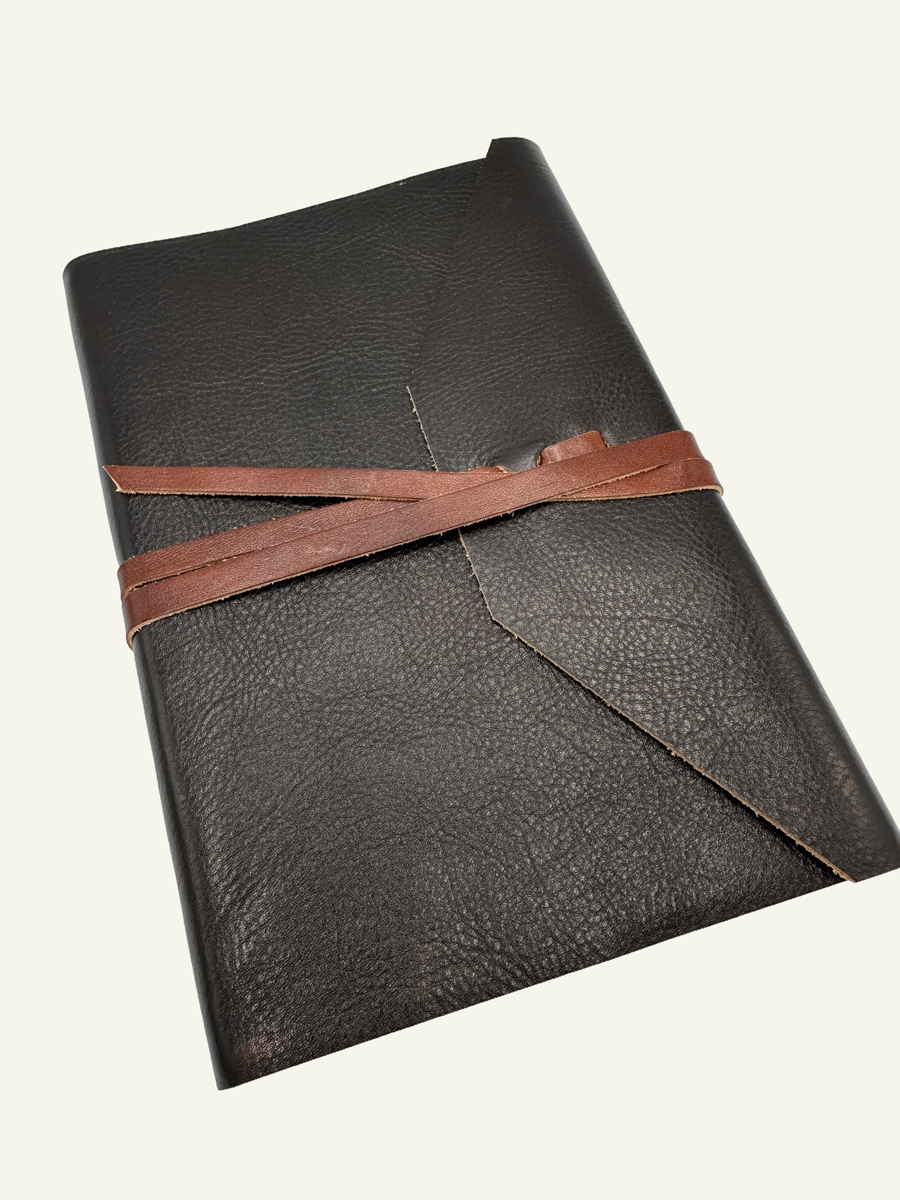 Angled view of handmade Italian leather wrap journal in deep espresso leather with wrap closure.