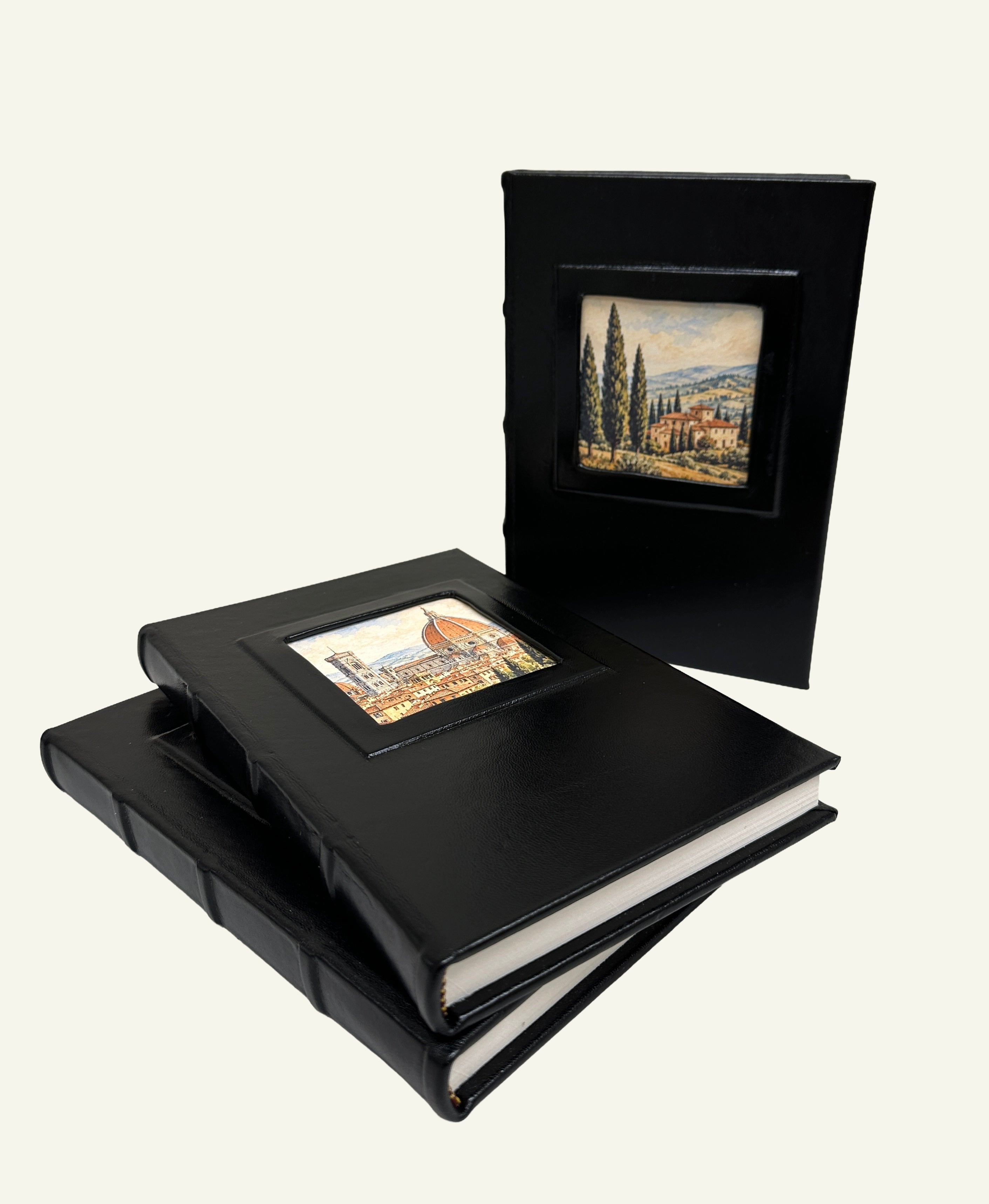 Three black leather journals displayed together with different Italian artwork in the portrait windows.