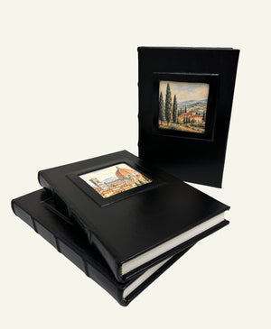 Three black leather journals displayed together with different Italian artwork in the portrait windows.