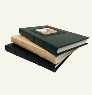 Close-up of stacked black, distressed sand, and forest green leather journals showing their textured spines.