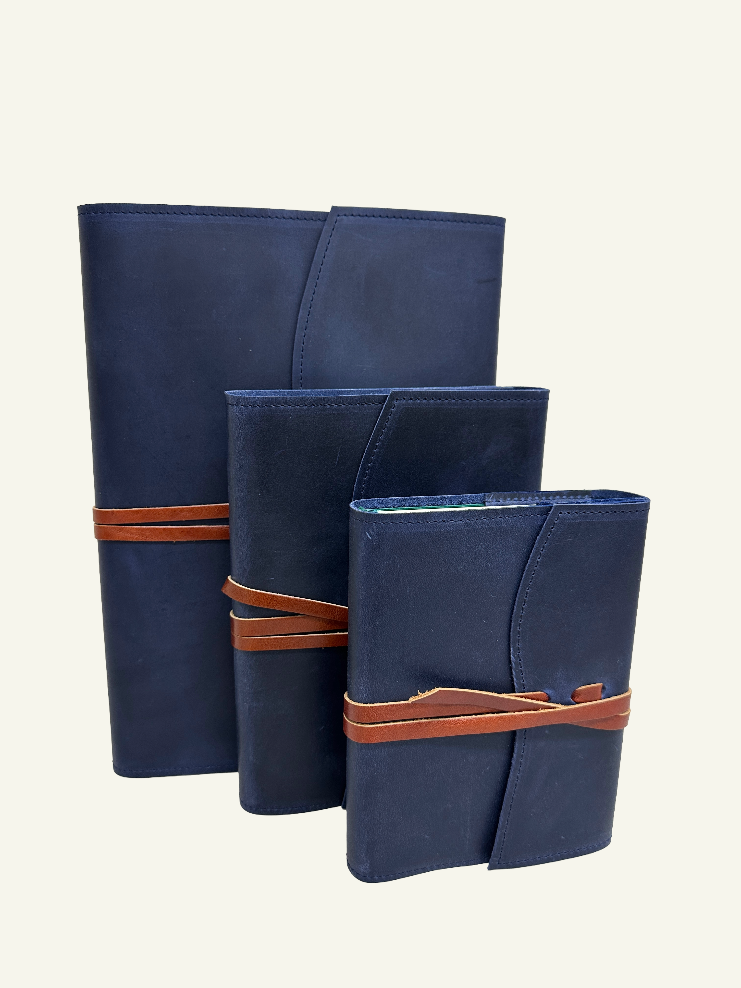 Three midnight blue softcover refillable leather journals displayed in different sizes. Small, medium & large