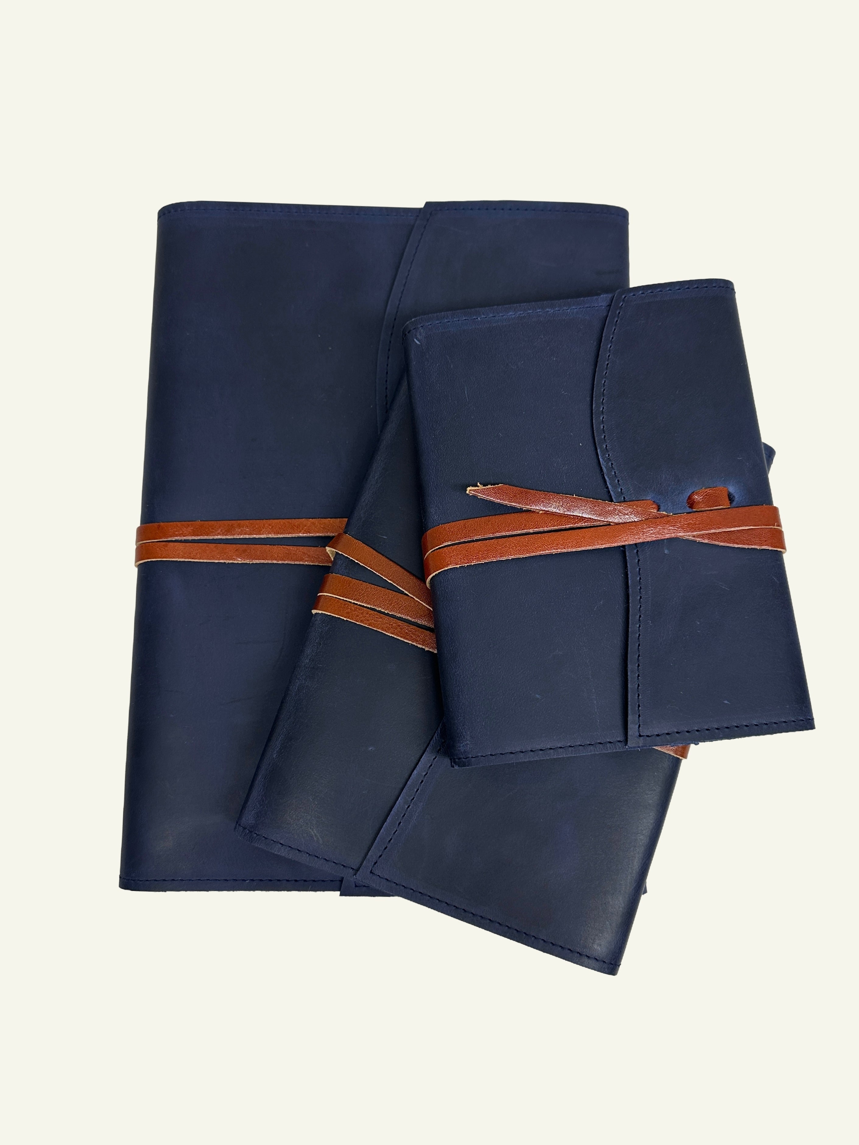 Midnight blue refillable leather journals shown in three sizes with brown leather wrap closures