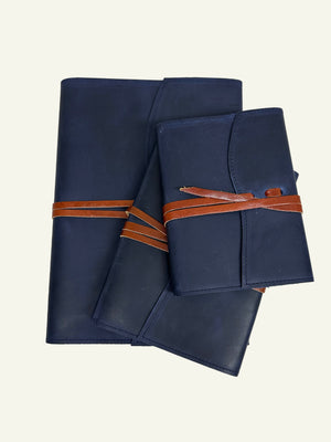 Midnight blue refillable leather journals shown in three sizes with brown leather wrap closures